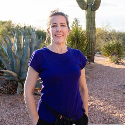 Owner of Traveling Therapeutic Massage, Rachel, standing outside by a saguaro and a cactus