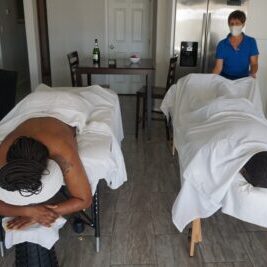 A couple laying two massage tables about to get a mobile massage at their Airbnb in Scottsdale AZ, with a massage therapist fixing the sheet